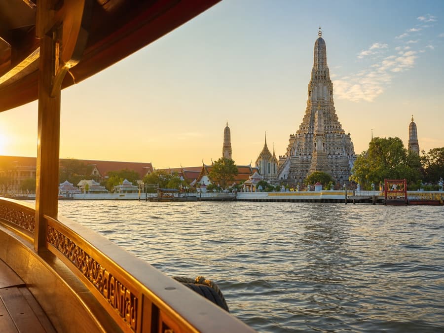 Wat Arun seen from a private teak boat on Bangkok's Chao Phraya River at sunrise